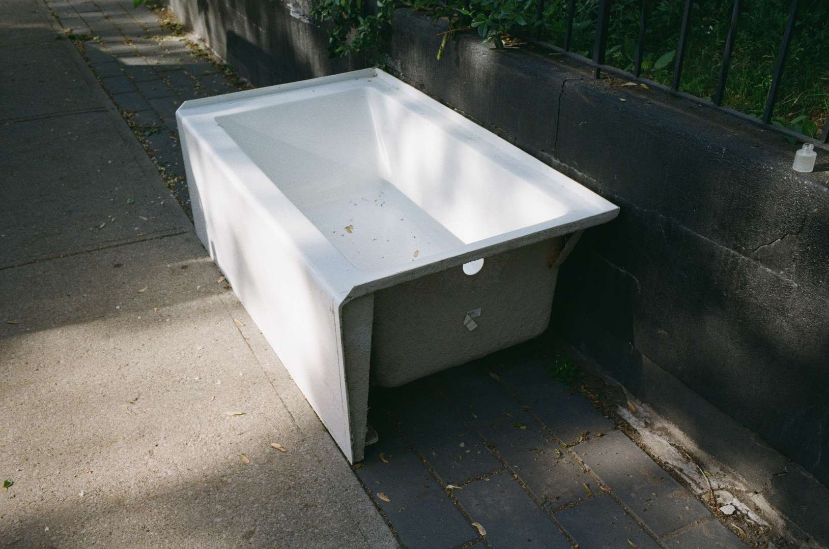 A colour photograph of a bathtub left on the sidewalk