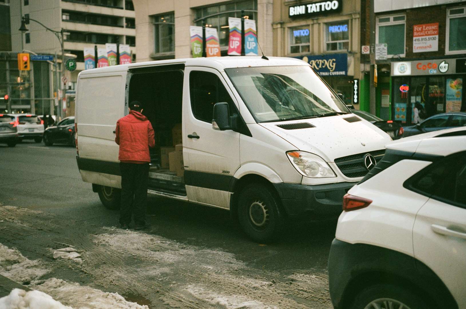 A colour photograph of a delivery man unloading goods in the street.